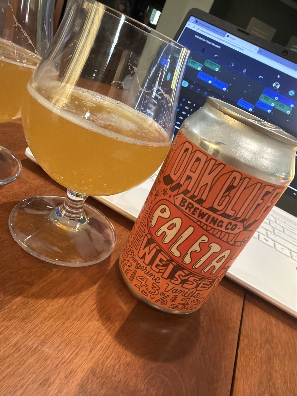 Tangerine Vanilla Paleta Weisse can beside a glass of golden beer.